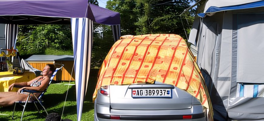 Car tent, awning and caravan pitched on grass at a Swiss campsite