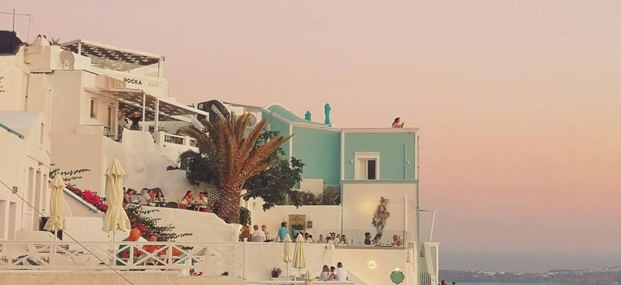 White Greek-island church with blue dome above the Aegean caldera view
