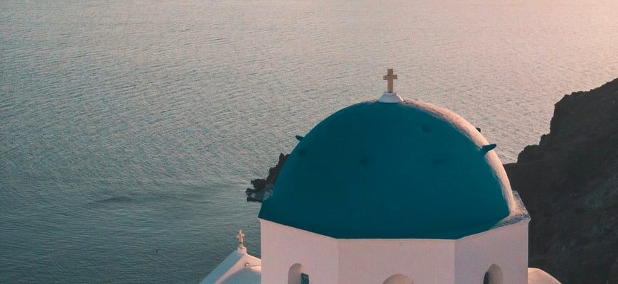 White-and-blue caldera houses in Oia, Santorini, with the Aegean Sea below