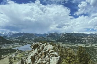 Colorado Rocky Mountains summer landscape with valley, lake, and snow-capped peaks visible from a hiking summit