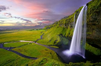 Icelandic waterfall cascading over moss-covered cliffs in dramatic landscape