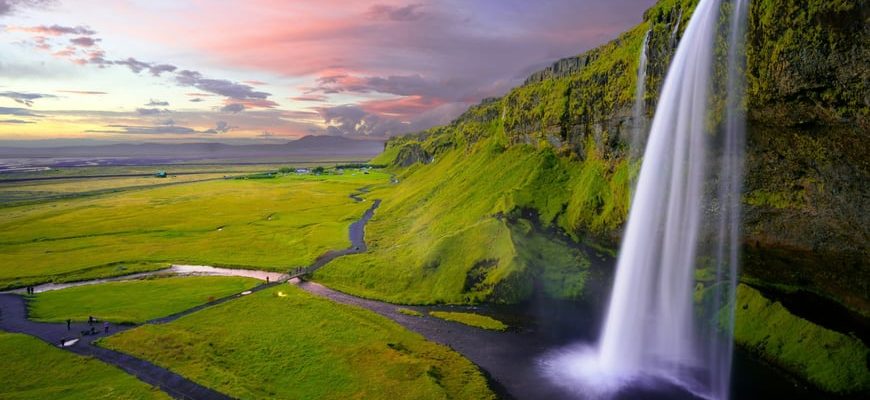 Icelandic waterfall cascading over moss-covered cliffs in dramatic landscape