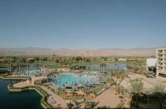 Aerial view of a Palm Desert resort with palm trees, pools, and Santa Rosa mountain backdrop