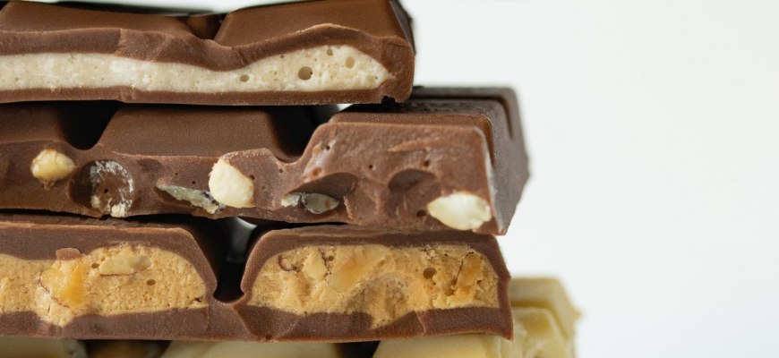 A stack of dark, milk and white chocolate bars with nuts and fillings