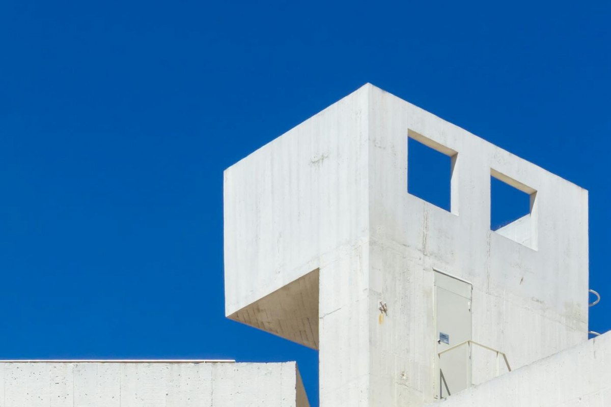 A white modern museum facade of clean geometric concrete against a blue sky