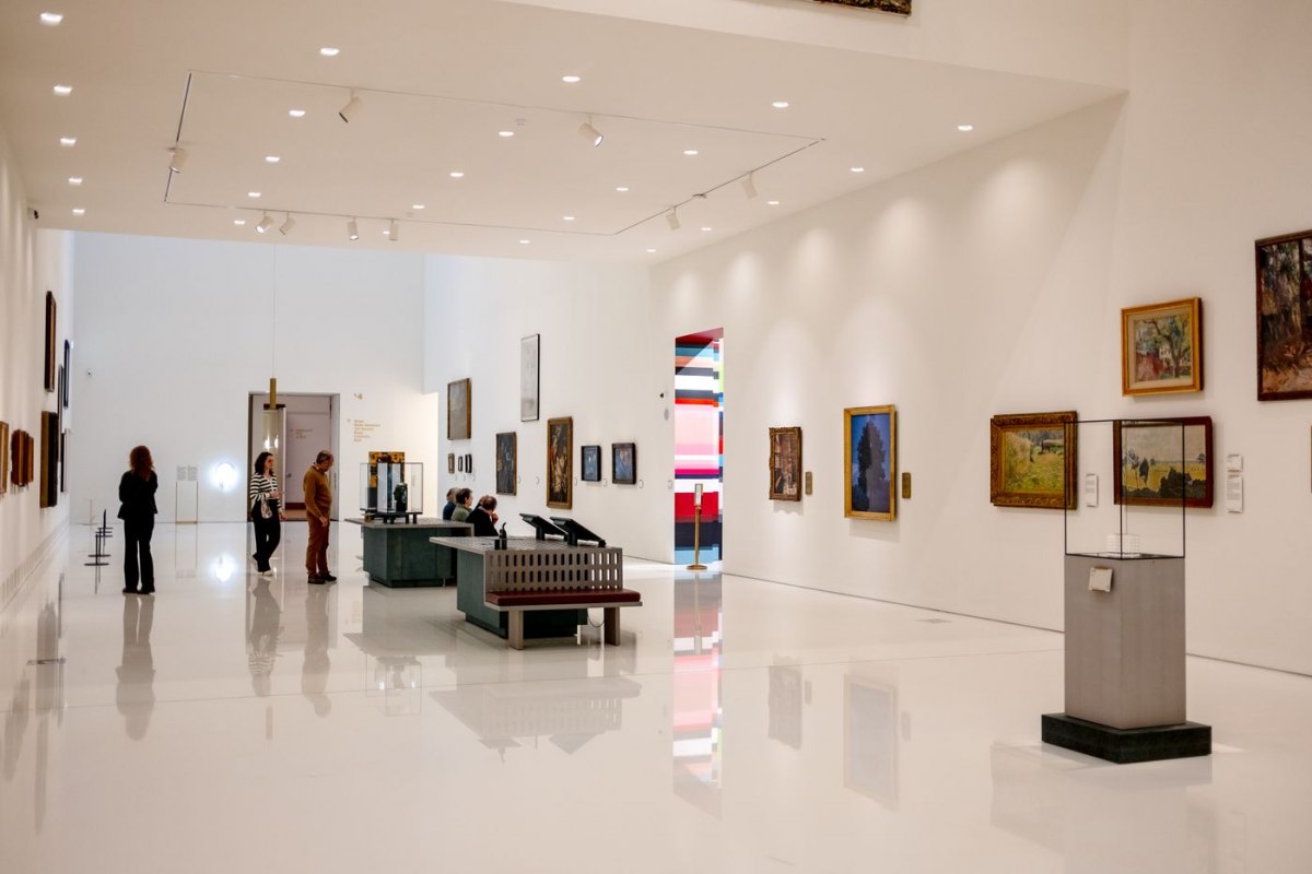 A bright gallery hung with framed paintings inside a Barcelona museum