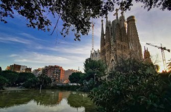 The towers of the Sagrada Familia reflected in the pond of Placa de Gaudi at dusk