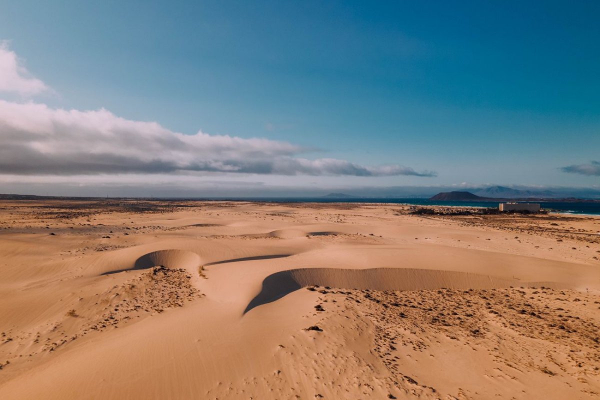 The Corralejo sand dunes meeting the turquoise sea with Lobos and Lanzarote on the horizon