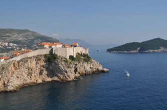 The old town walls of Dubrovnik on the cliffs above the blue Adriatic Sea