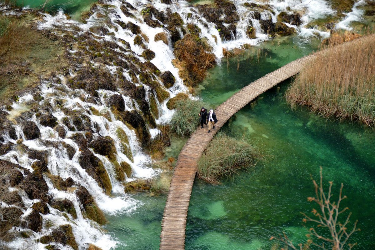 Visitors on wooden boardwalks over the turquoise waters of Plitvice Lakes