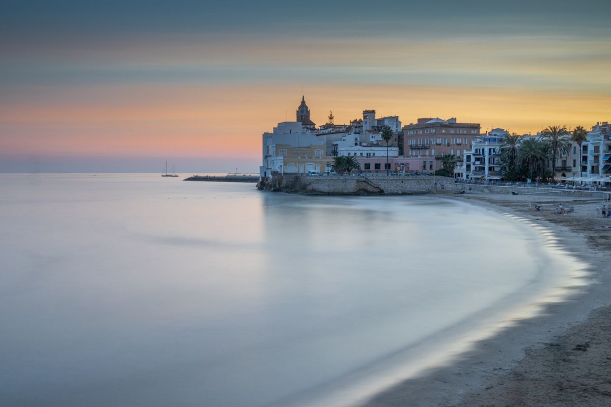 The beach of Sitges with the church on the headland at dusk
