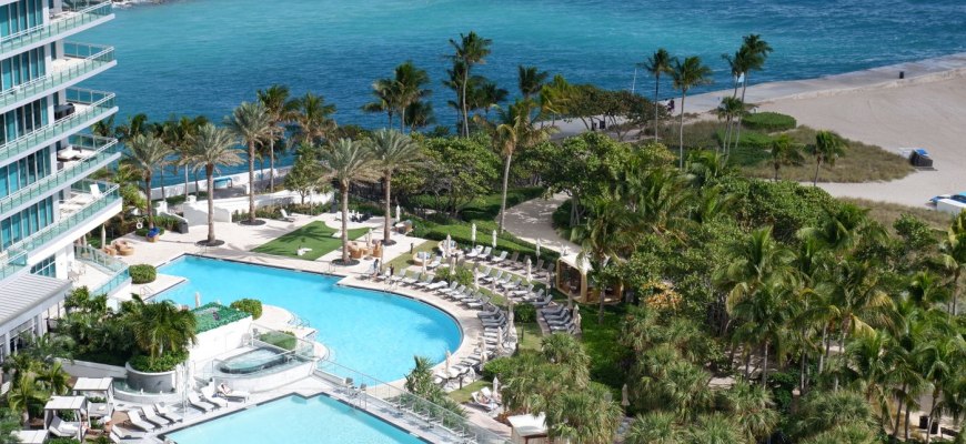 Aerial view of a Florida beachfront resort with two pools, palm trees and the ocean