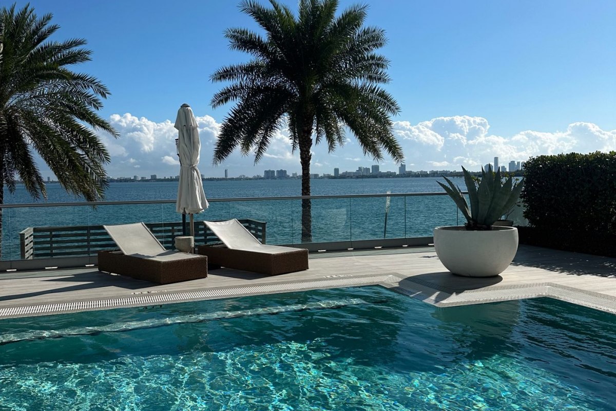 A resort poolside framed by palm trees overlooking the sea in Florida