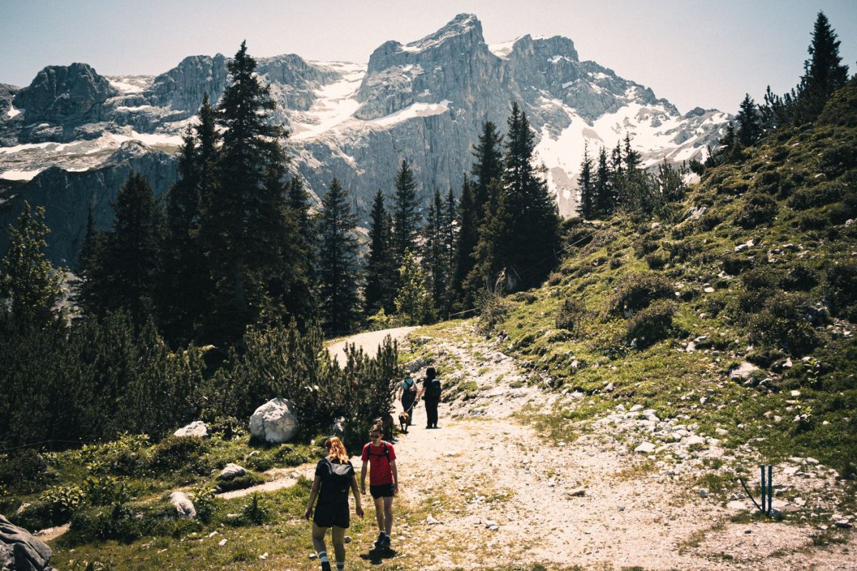 Hikers on a mountain trail below snow-capped peaks in the French Alps