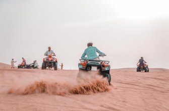 A quad bike crossing sandy dune terrain in bright sun