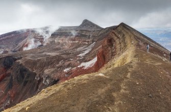 Hikers crossing a volcanic ridge with wide views