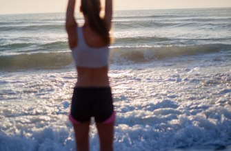 A woman in a yoga pose on a beach at sunrise