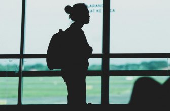 A lone traveller with a backpack silhouetted in an airport terminal