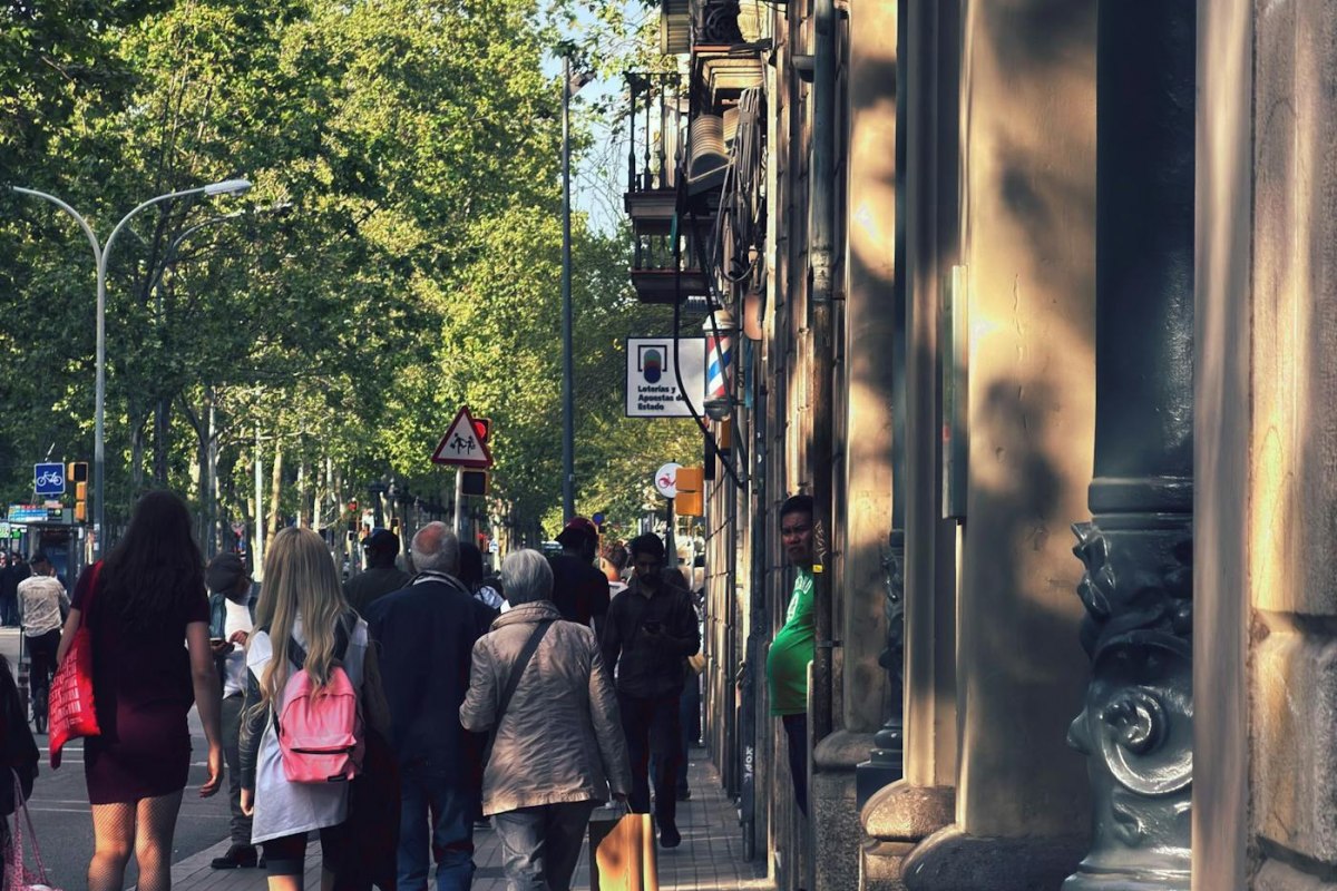 Shoppers walking past boutiques on a tree-lined Barcelona shopping street