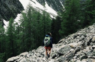 A hiker carrying a backpack on a rocky alpine trail in the mountains