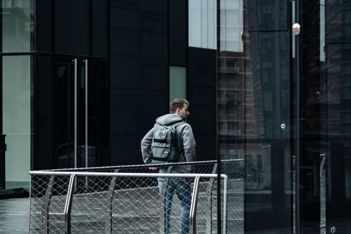 A person carrying an urban commuter backpack through a modern city plaza