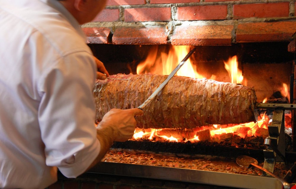 A cook slicing Turkish doner kebab from a vertical spit