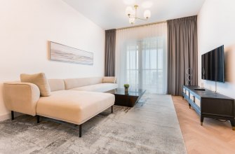 A bright holiday apartment living room with a beige sofa and balcony doors