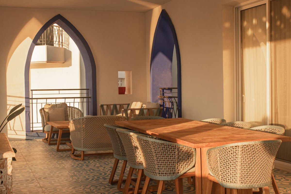 A tiled Mediterranean apartment terrace with arches and a dining table