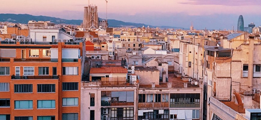 A rooftop terrace looking over Barcelona residential blocks toward the Sagrada Familia at sunset